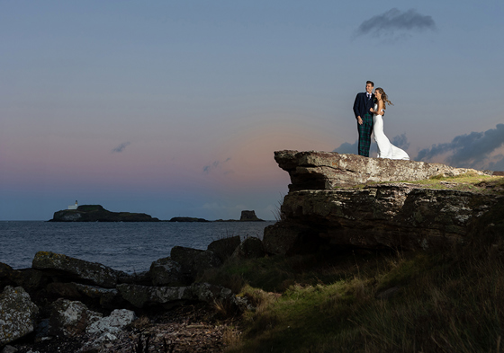 Bride and groom looking out to water on cliffside